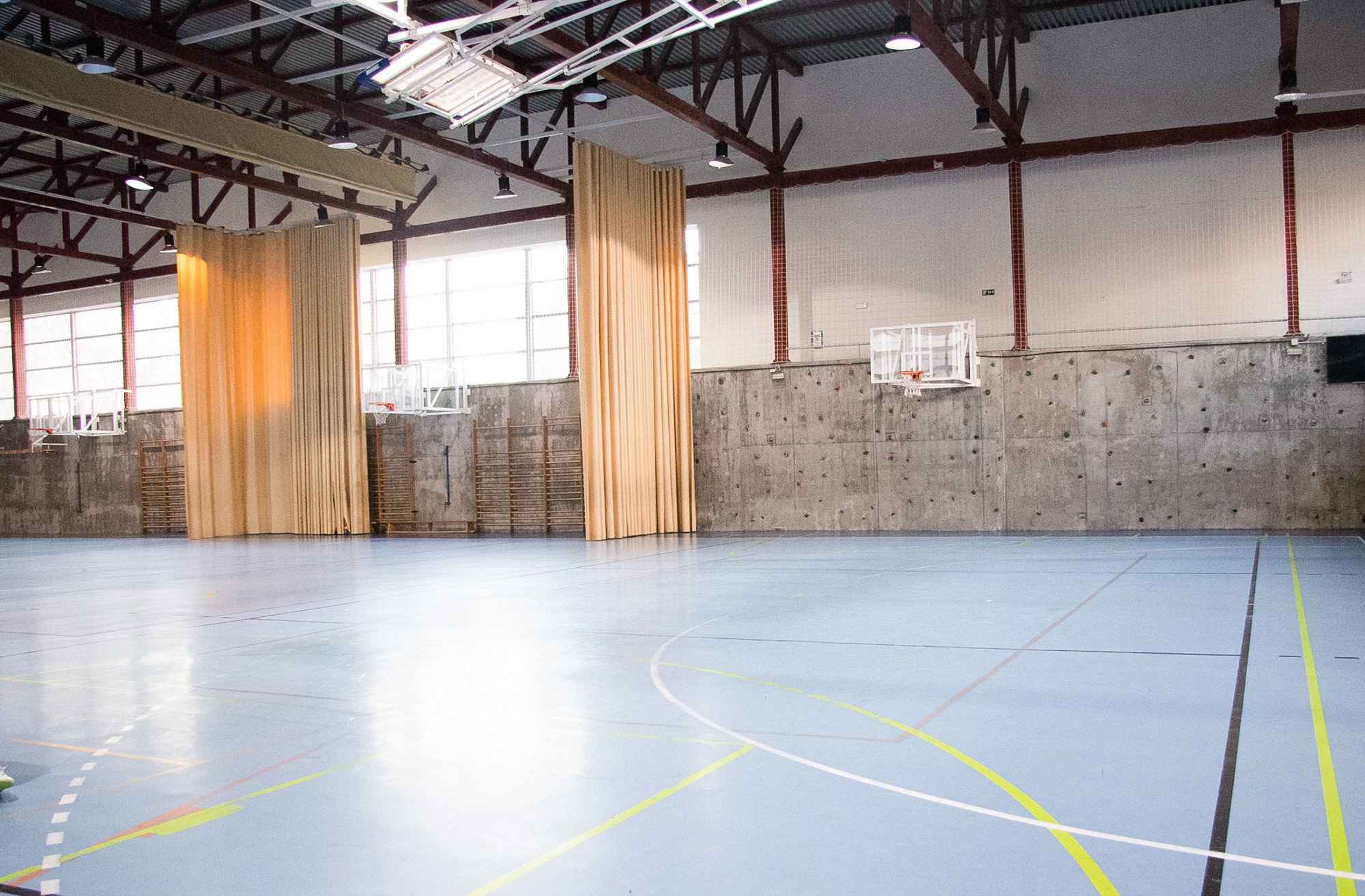 Zona lateral del pabellón deportivo, instalaciones del colegio internacional jh newman con canastas y espacio multiusos.
