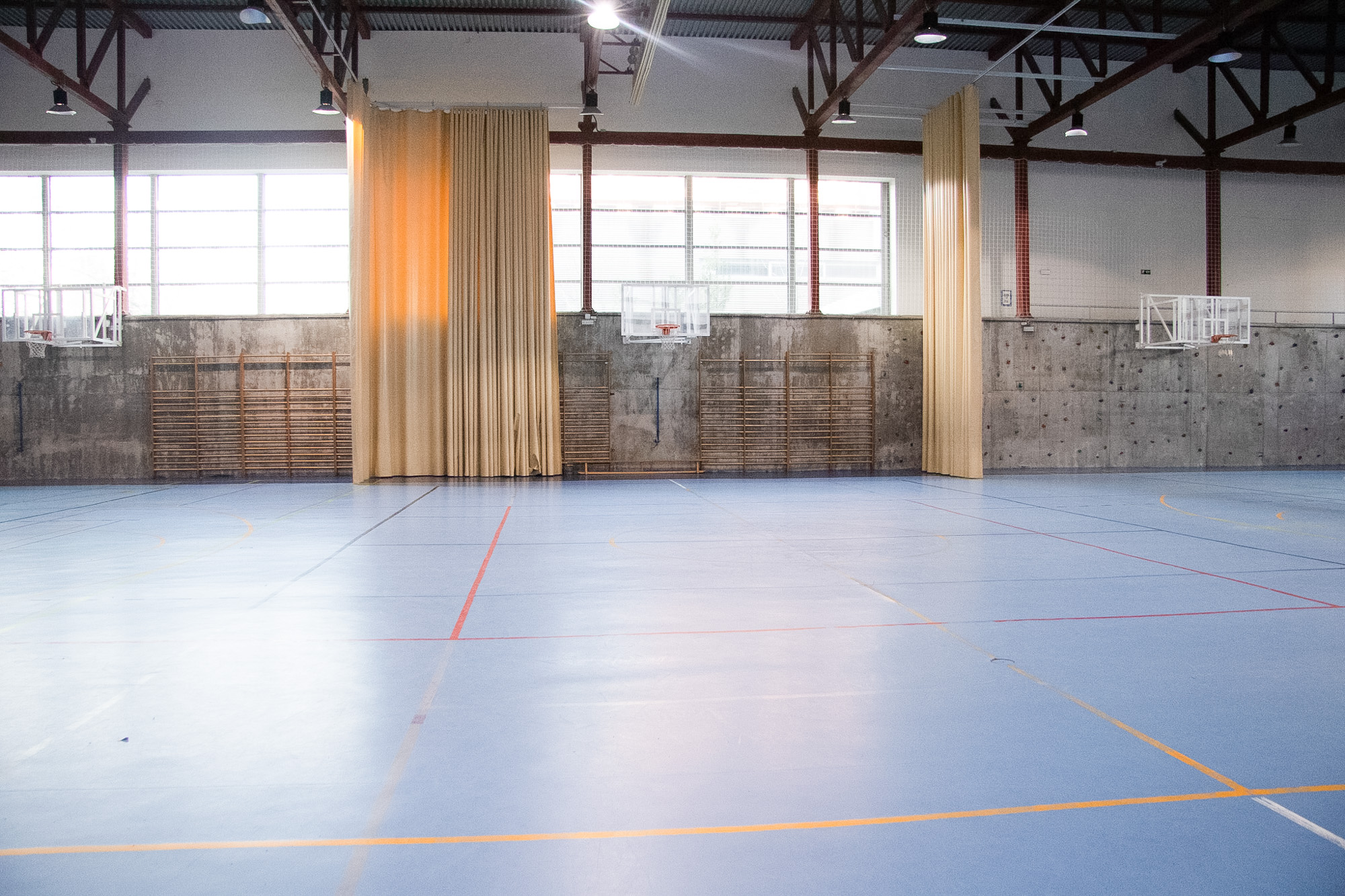 Vista general del polideportivo interior de las instalaciones colegio newman con canchas y cortinas divisorias.