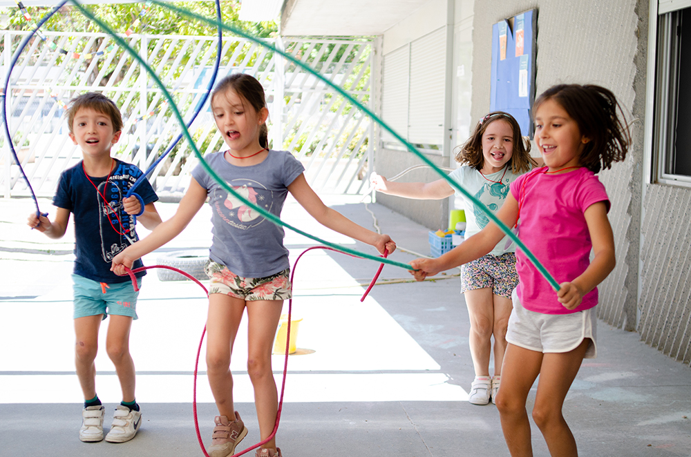 Niños disfrutando de juegos motores y actividad física en el patio como parte de su desarrollo en educación infantil.
