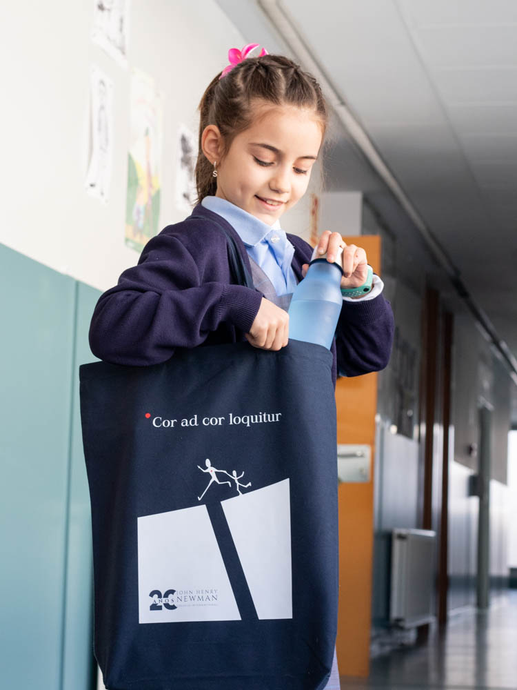 Alumna de educación infantil con material escolar del Colegio Newman en un pasillo del centro.