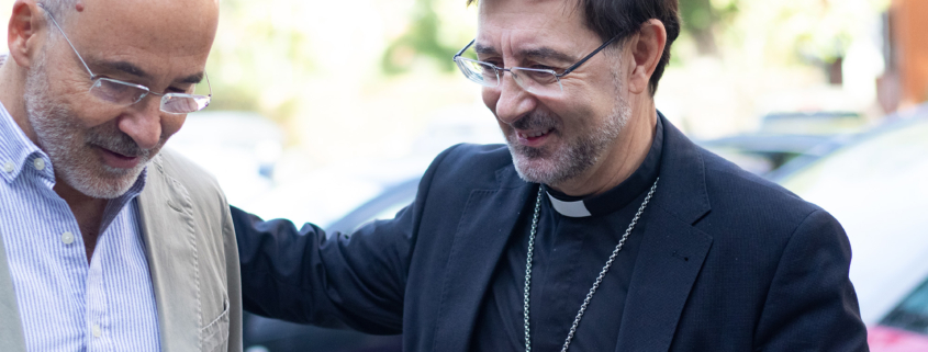 Sacerdote conversando con un adulto en exterior durante una jornada de orientación educativa del centro.