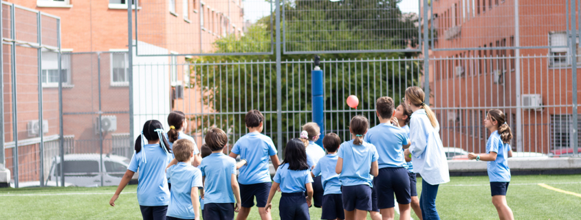 Grupo de alumnos en pista exterior realizando actividad deportiva con balones y porterías, centro deportivo newman.